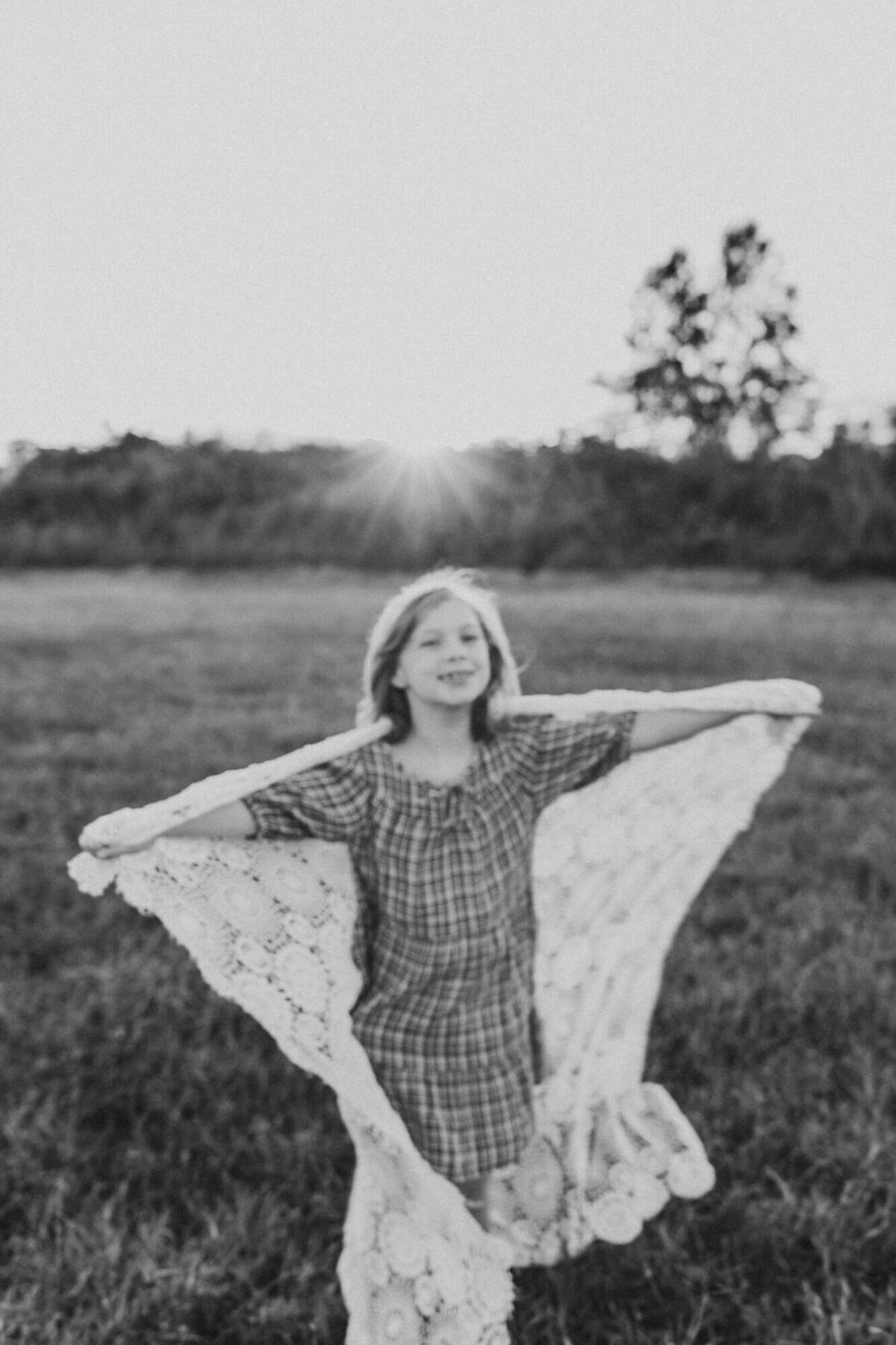 Artistic effect of camera drag in black and white image of little girl with arms stretched out.