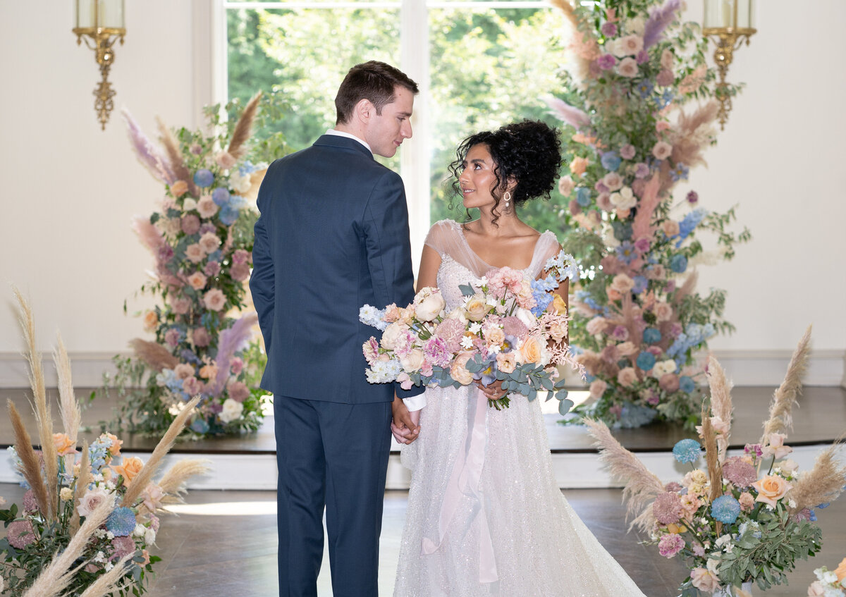 A couple stands inside the chapel at Couple in Park Château Estate & Gardens surrounded by flowers.