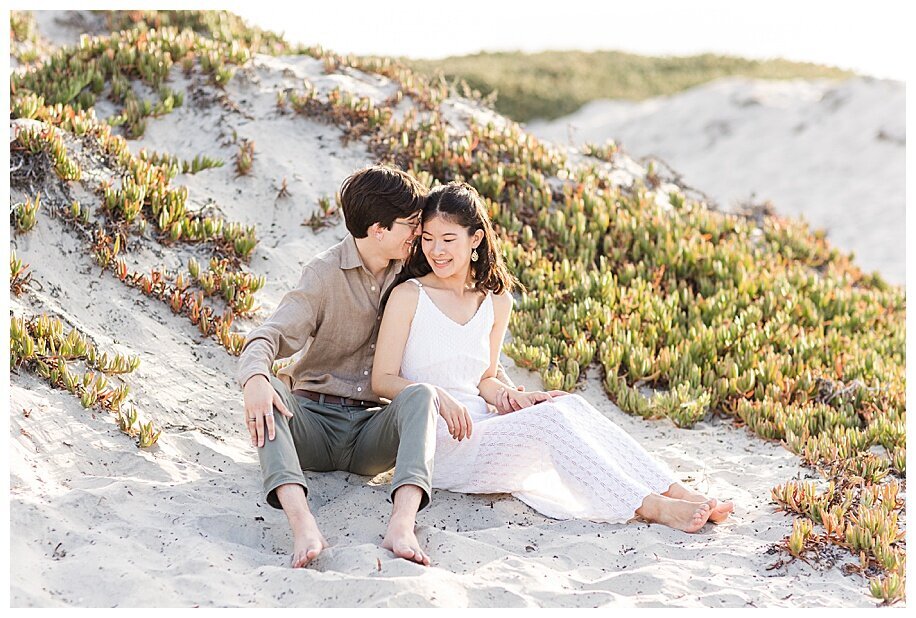 engaged couple sitting in coronado sand dunes
