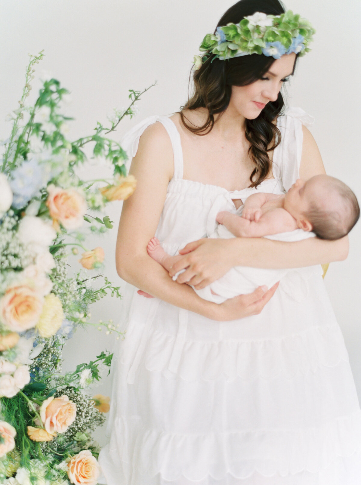 Mother with flower crown holding newborn baby