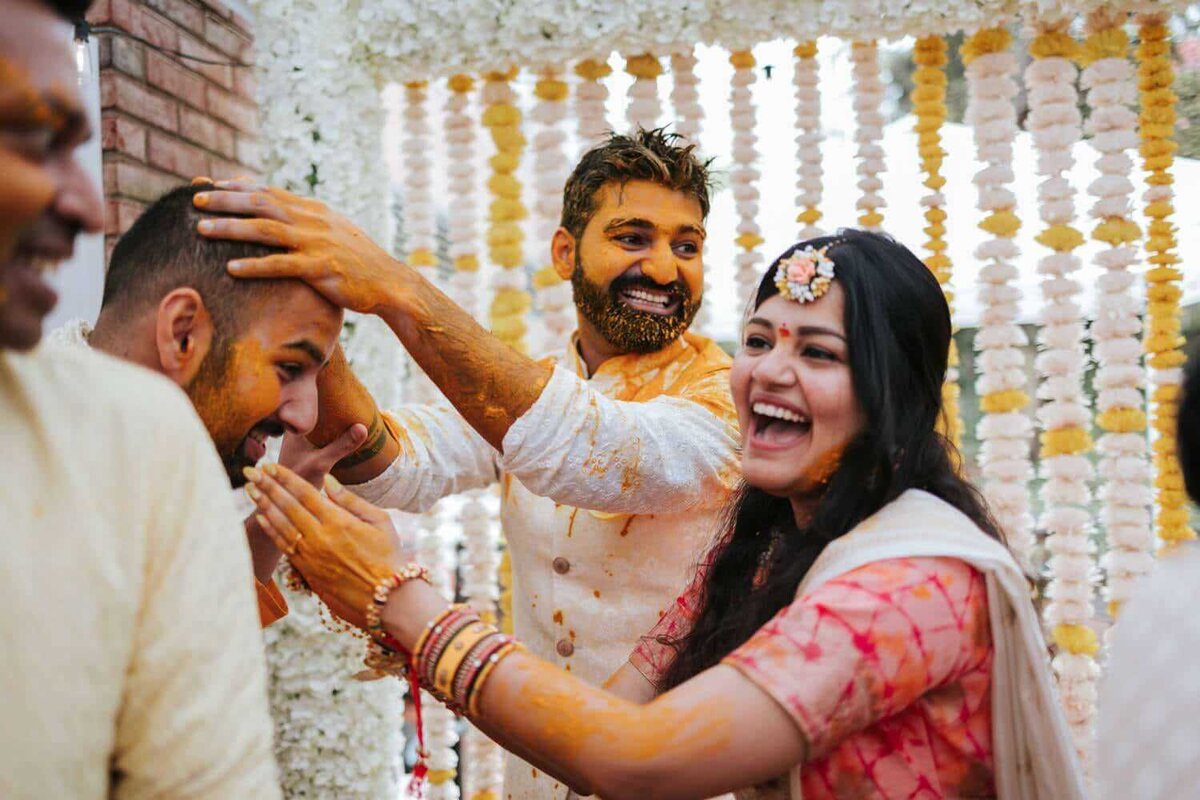 The groom is covered in turmeric by friends and family in Connecticut.