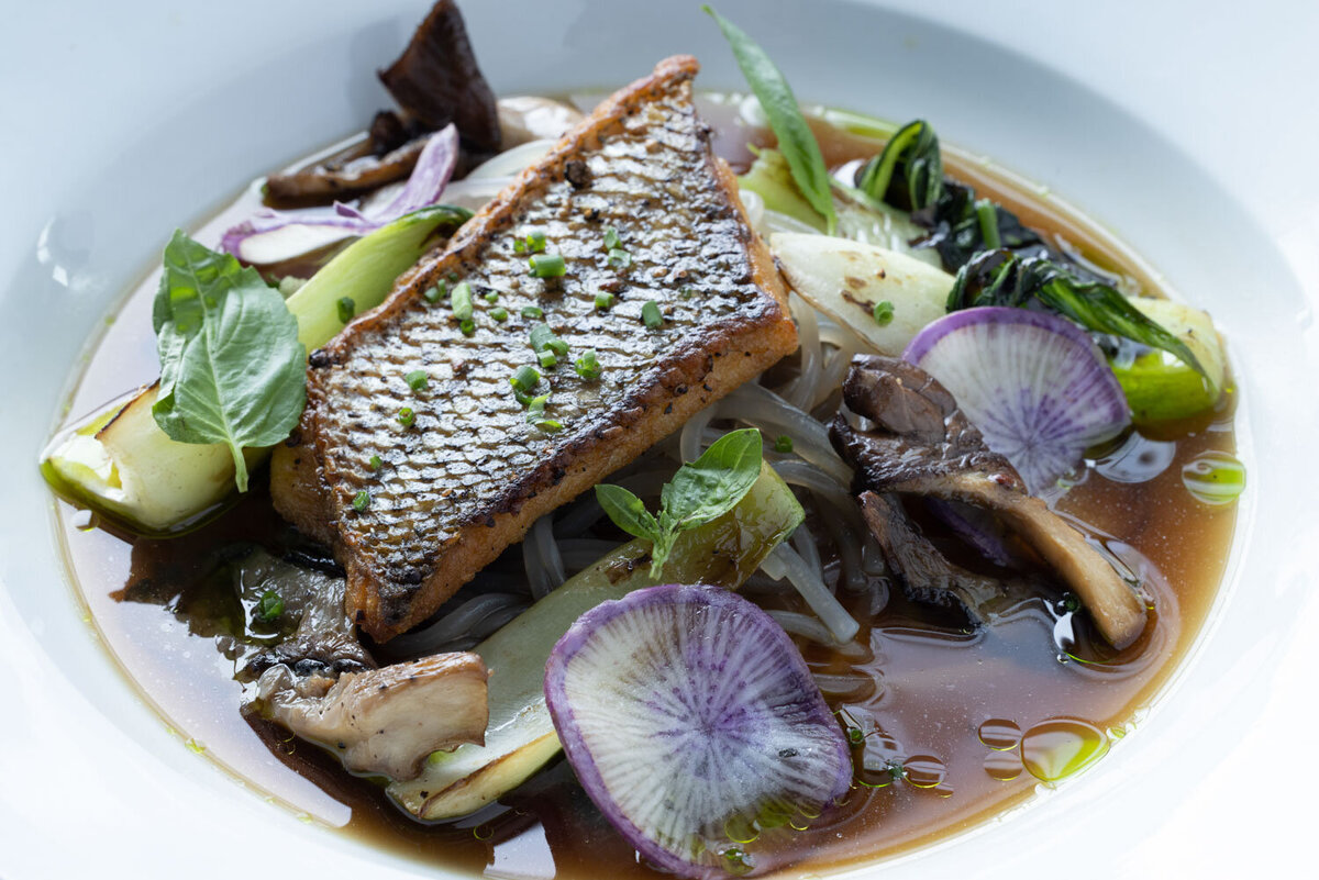 Seared fish with radish slices and mushrooms in broth