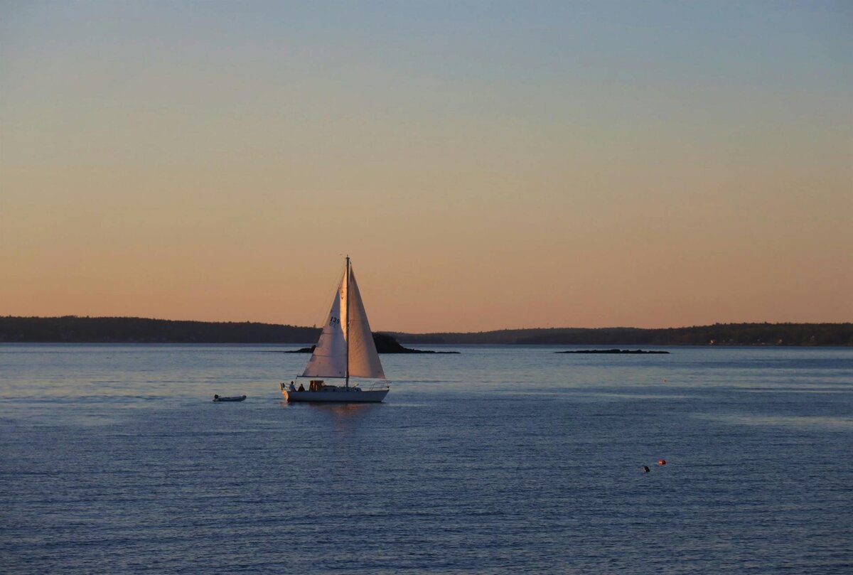Sailboat gliding through calm water at sunset, symbolizing peaceful forward motion through trauma healing with EMDR Intensives