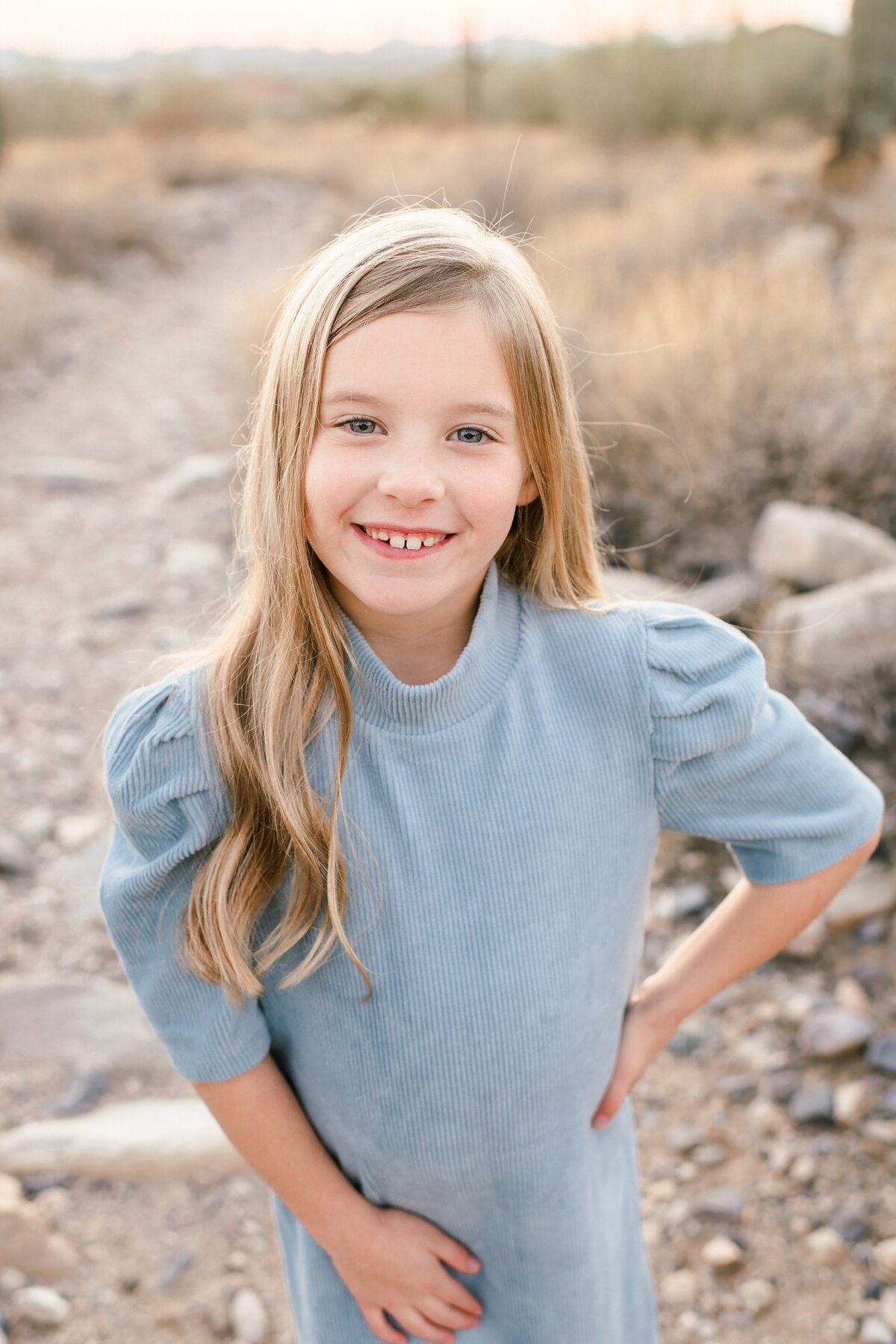 little girl standing in the arizona desert smiling at the camera