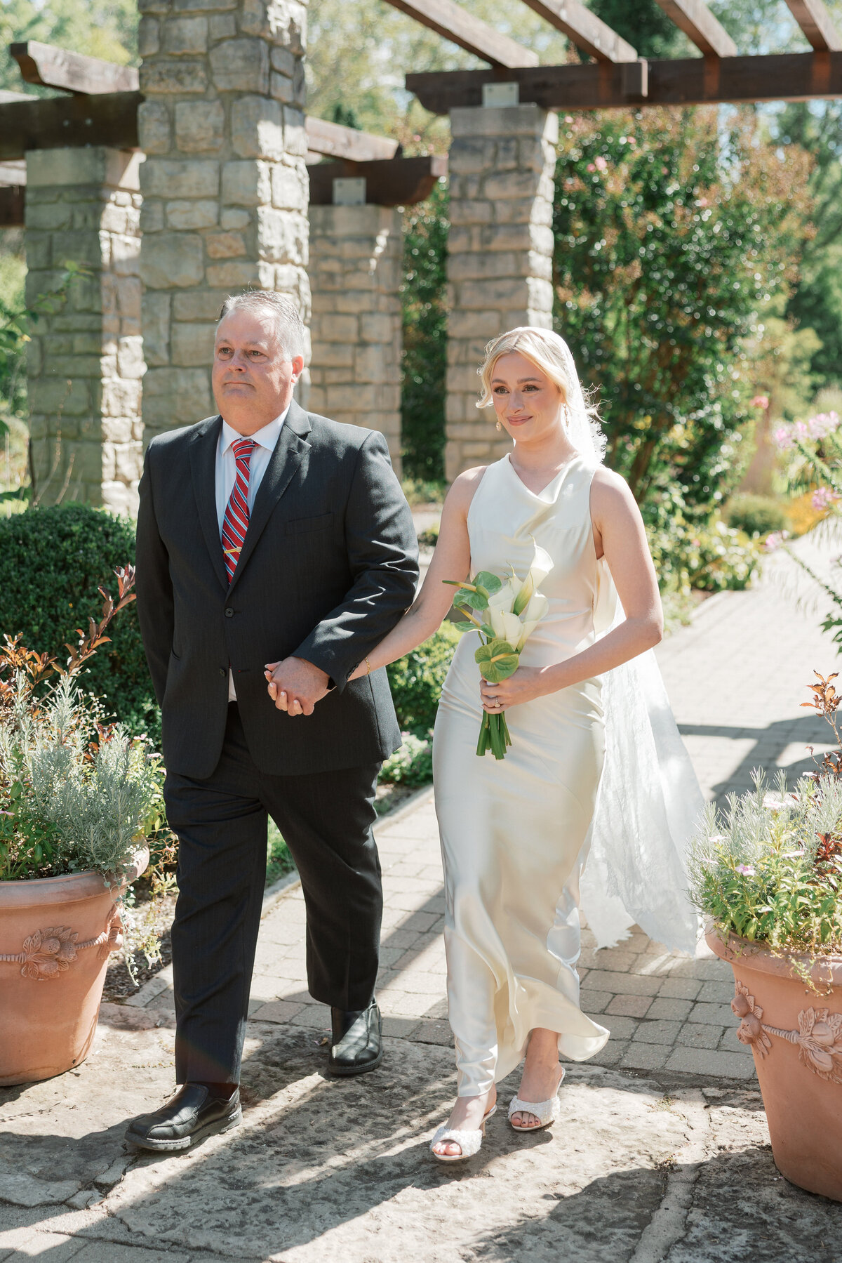 Bride walks down the aisle in Dayton, Ohio, holding calla lily bouquet, photo by Philly-based wedding photographer.