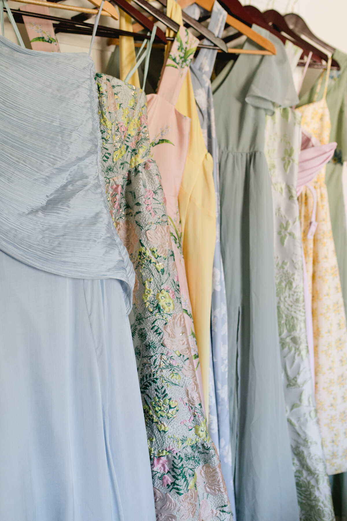 Assorted pastel bridesmaid dresses hanging.