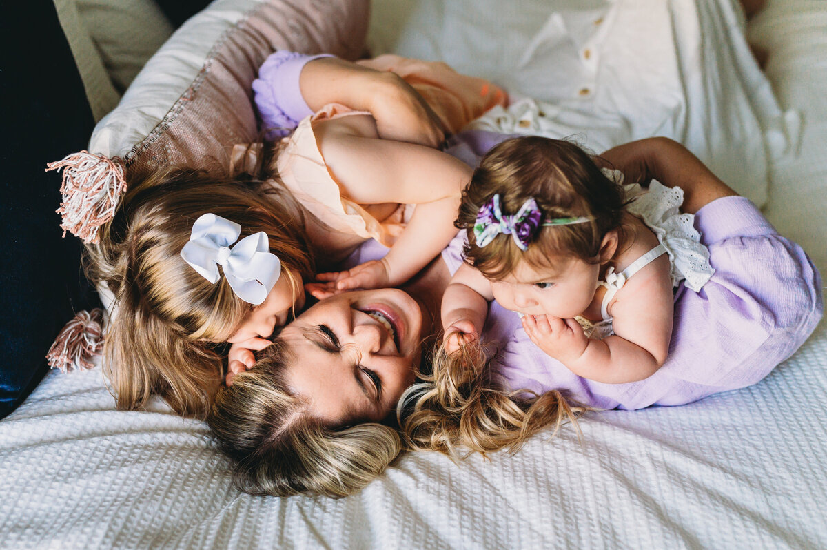 mom with two daughters snuggled up in bed