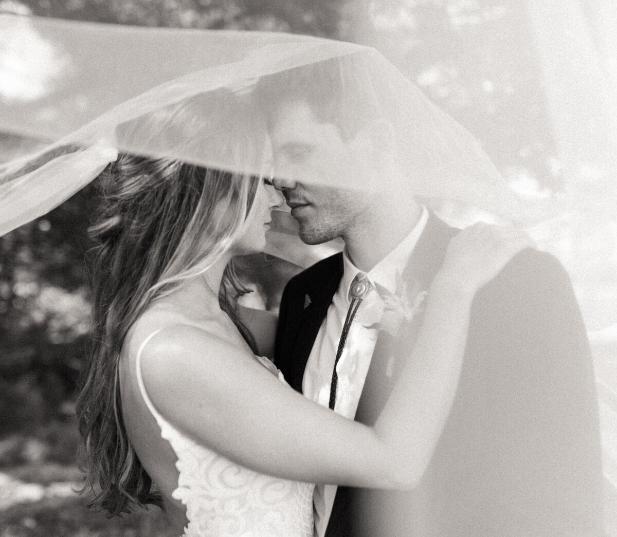 Bride and groom embracing each other as the wind blows her cathedral veil over them