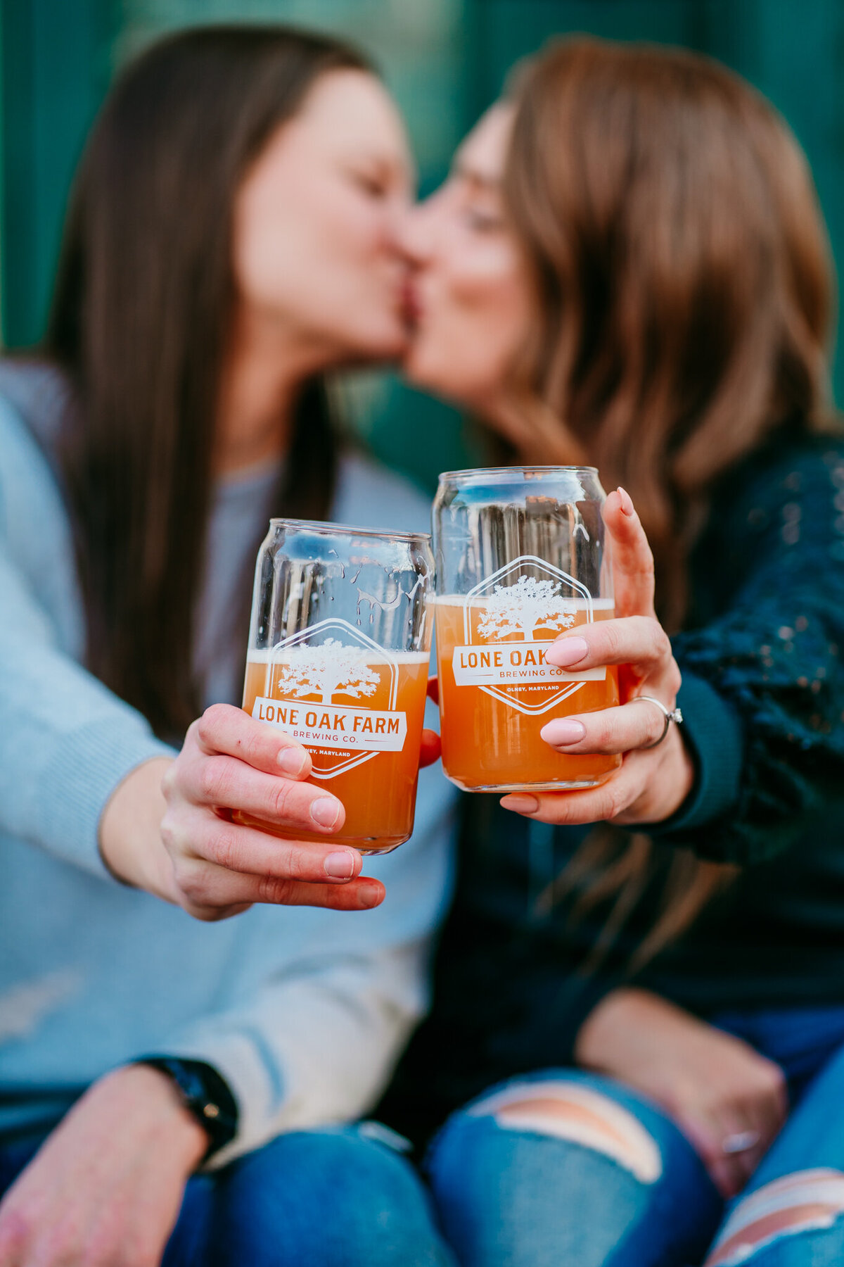Couple sharing a beer and kissing during a cozy fall session