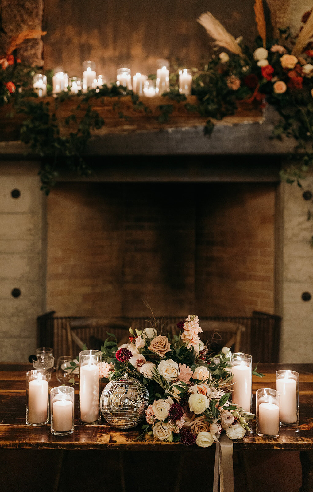 Flowers and candles on mantle with bridal bouquet and disco ball at the barn at  Brasada Ranch