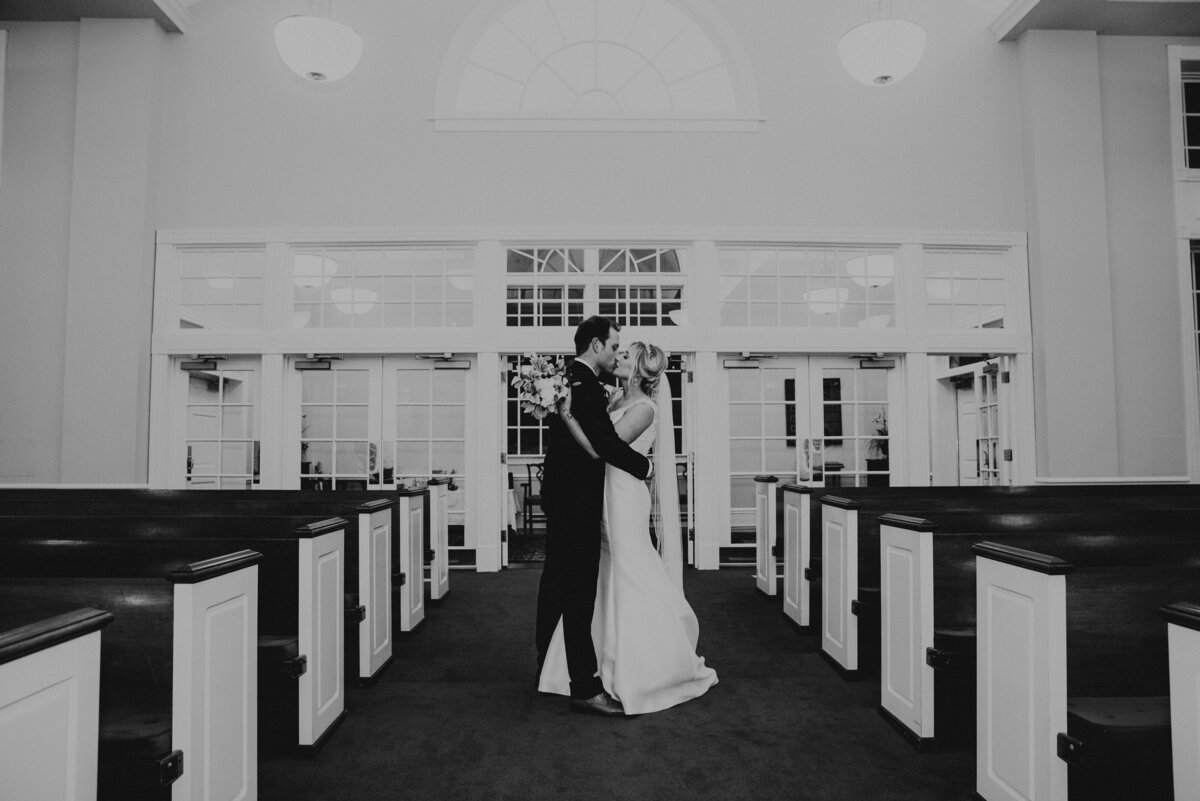 A bride and groom kiss in the aisle