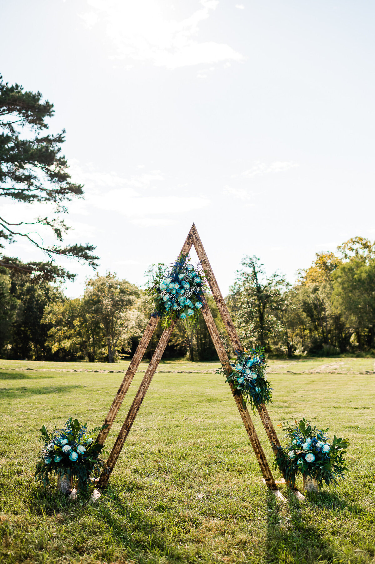 wedding decor idea for ceremony space with a wooden triangular arch in a dark stain with blue florals decorating the arch at a Shenandoah wedding venue