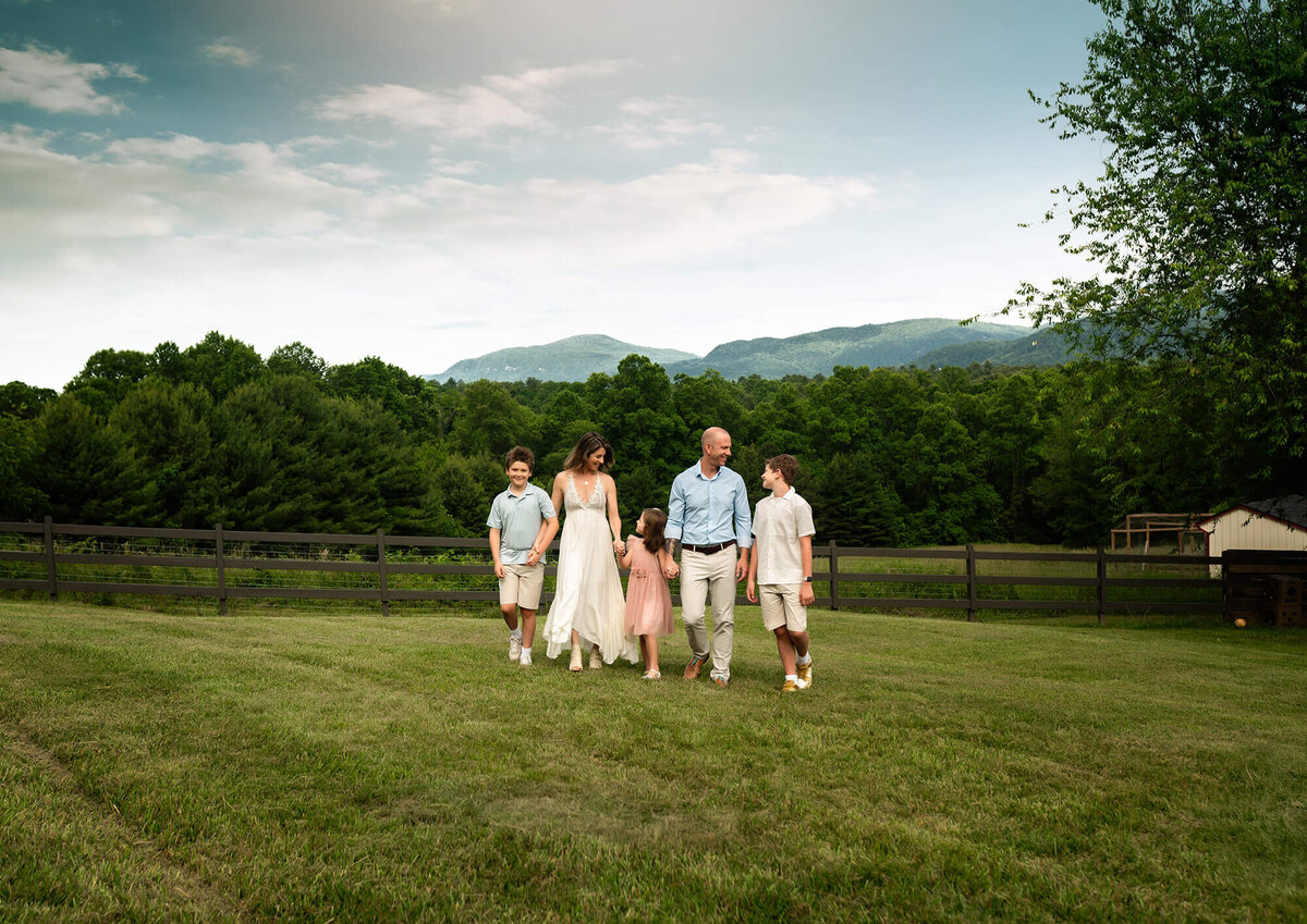 A family of five holds and hands and walks across the grass behind their home in Fairview, NC. 