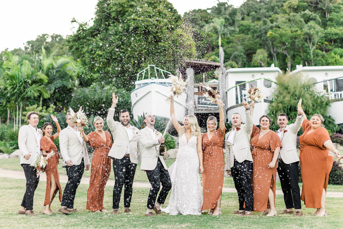bridal party cheer as groom pops champange