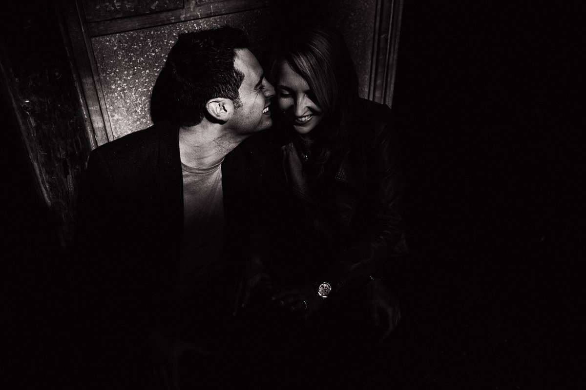 A black and white photo of a couple sat in a shaft of light in Manchester