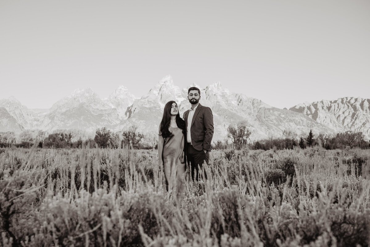 black and white photo of engaged couple in Jackson Hole Wyoming in the fall standing close together in a field