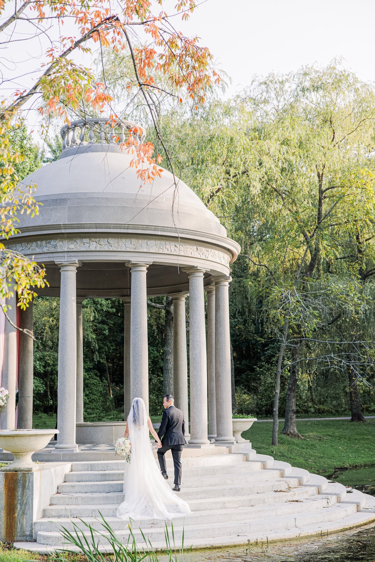 Bride and groom holding hands and walking up tempietto steps representing beautiful Boston wedding photos