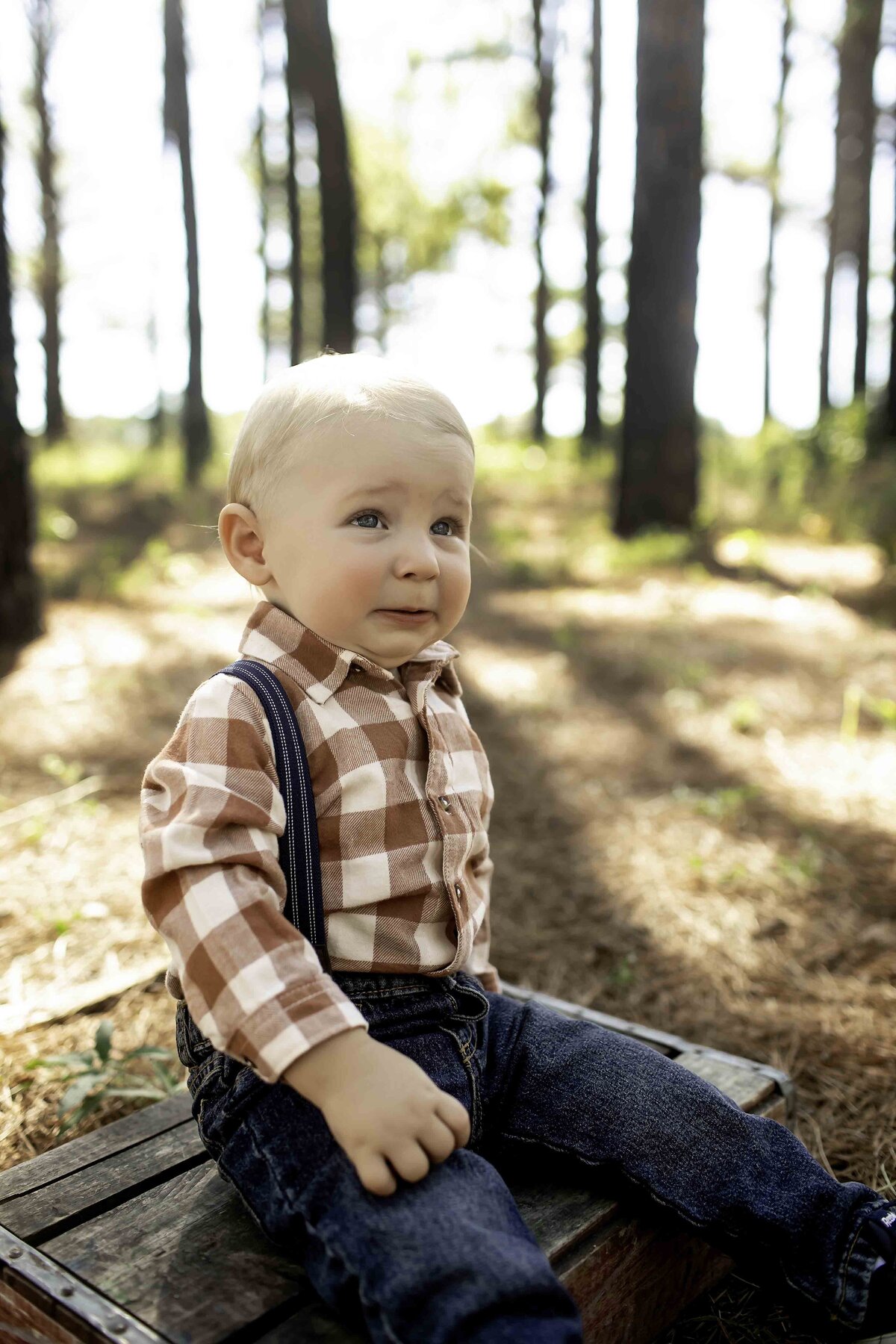 Birthday boy in suspenders and overalls, walking through the pine tree forest with a curious look