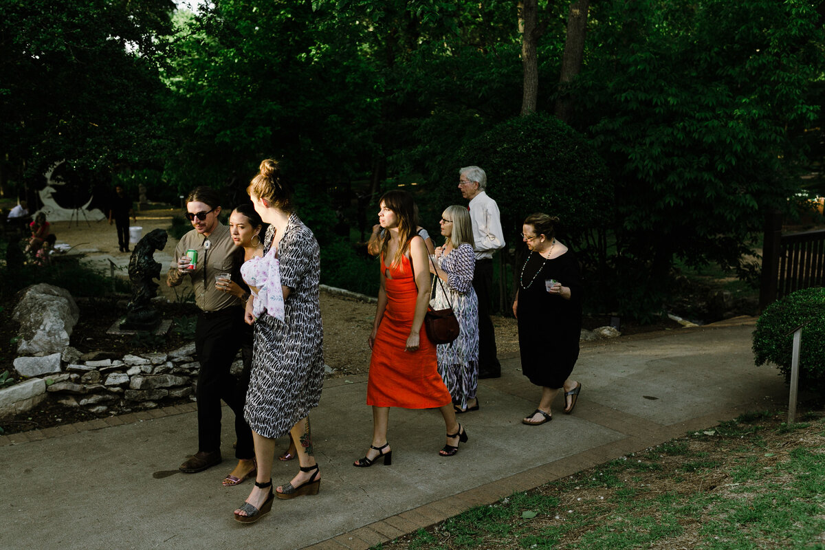 Wedding guests walking along path at Umlauf Sculpture Garden, Austin
