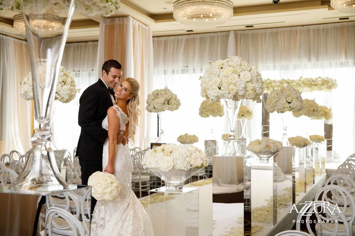 Bride and groom standing in wedding ceremony aisle lined with large white flower arrangements on top of mirrored pedestals at Four Seasons Seattle