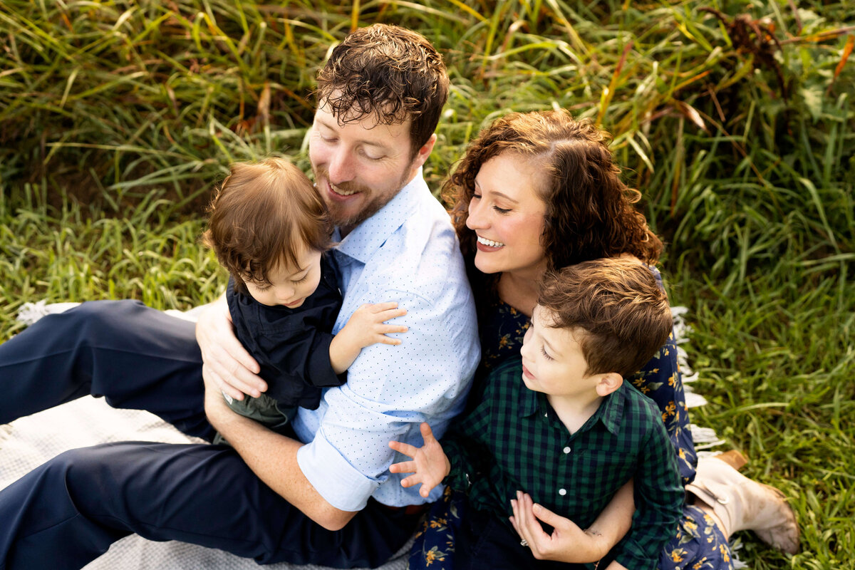 Family of four snuggling in field while sitting down