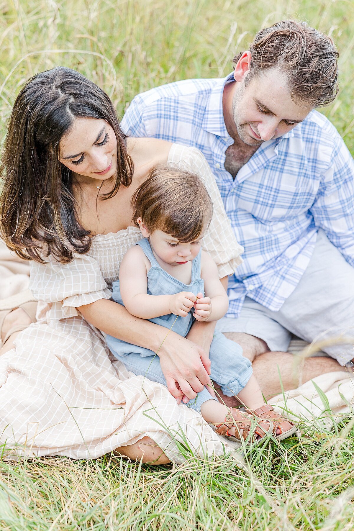 family sits in grass during Family photo session with Sara Sniderman Photography at Heard Farm in Wayland Massachusetts