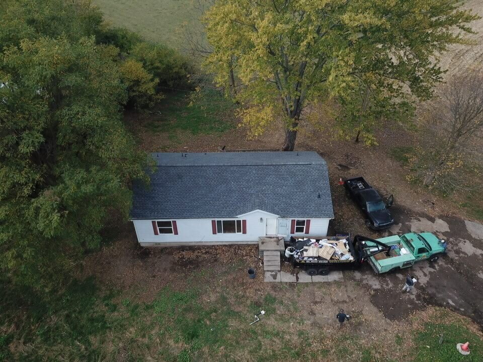 Roof replacement in progress on a small house by Black Bear Roofing.