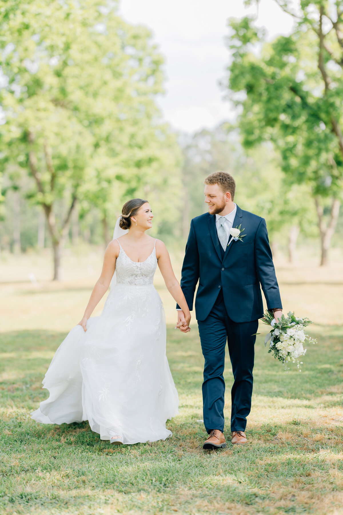 bride and groom holding hands and walking on farm land on their wedding day