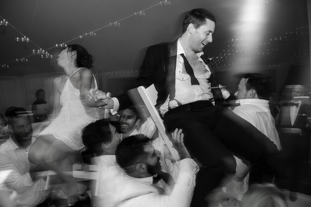 A couple dances on chairs at a destination wedding in Vermont