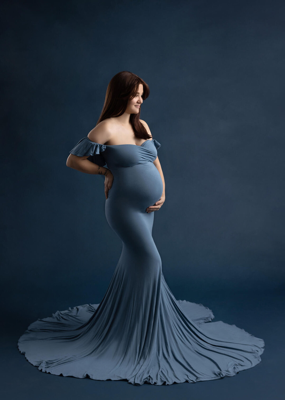 preagnant woman wearing a blue dress holding her belly