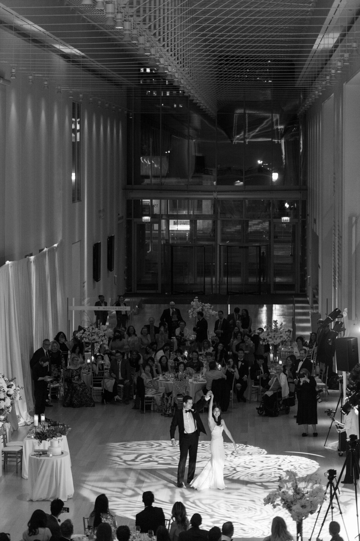 A stunning wide black and white photo of a newlywed couple twirling during their first dance at the Art Institute of Chicago.