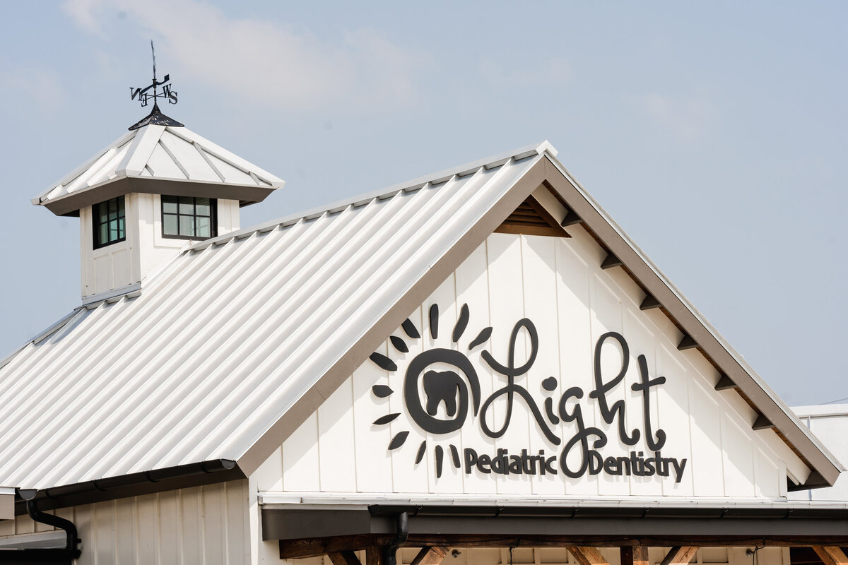 signage on building exterior with metal gable roof and cupola
