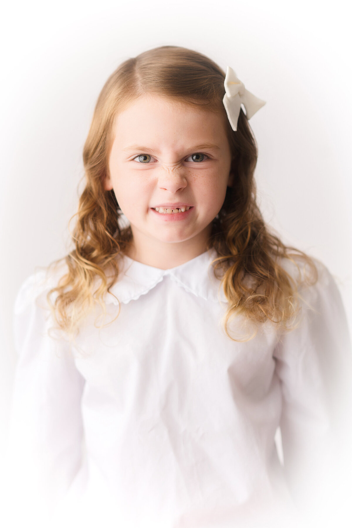 Young girl crinkles her nose at the camera during Heirloom Photoshoot in Charleston.