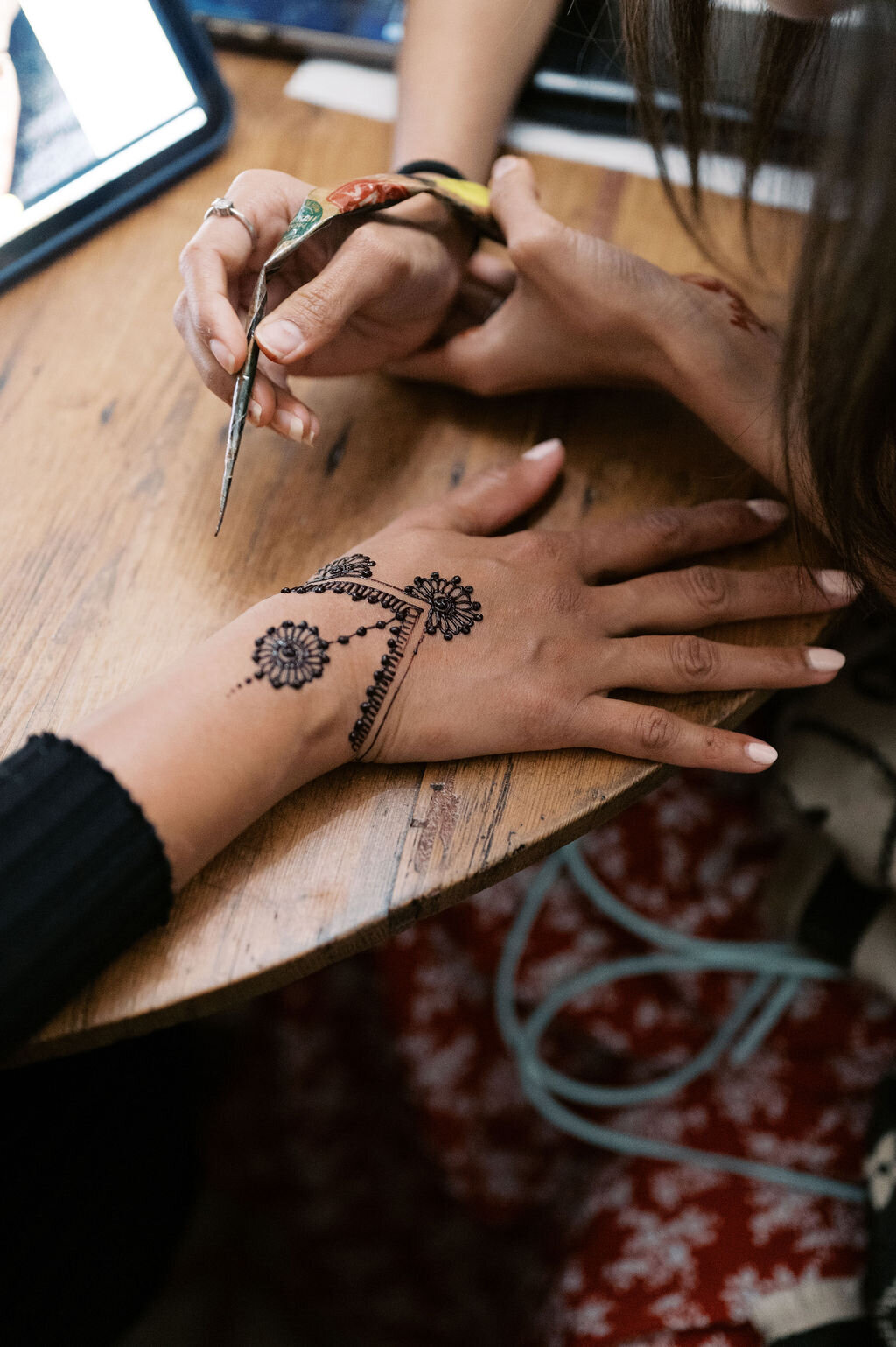 Close-up of henna being carefully applied to a guest’s hand during the wedding welcome party.