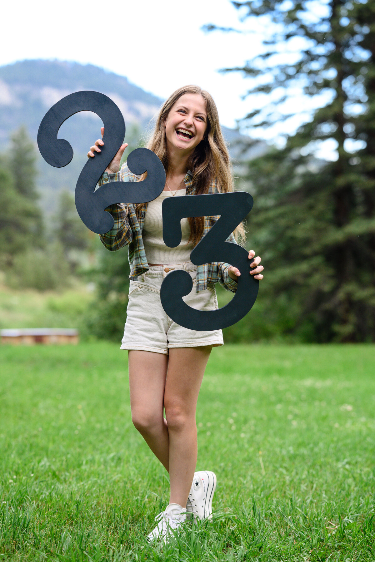 2023 senior hold large wooden numbers of 2 and 3 laughing at senior photos denver
