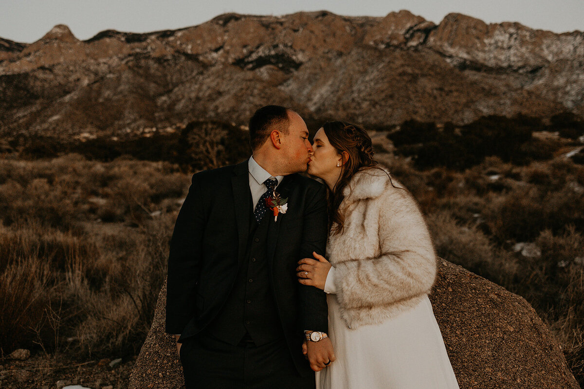 newlyweds holding each other close on the snowy Sandia mountains