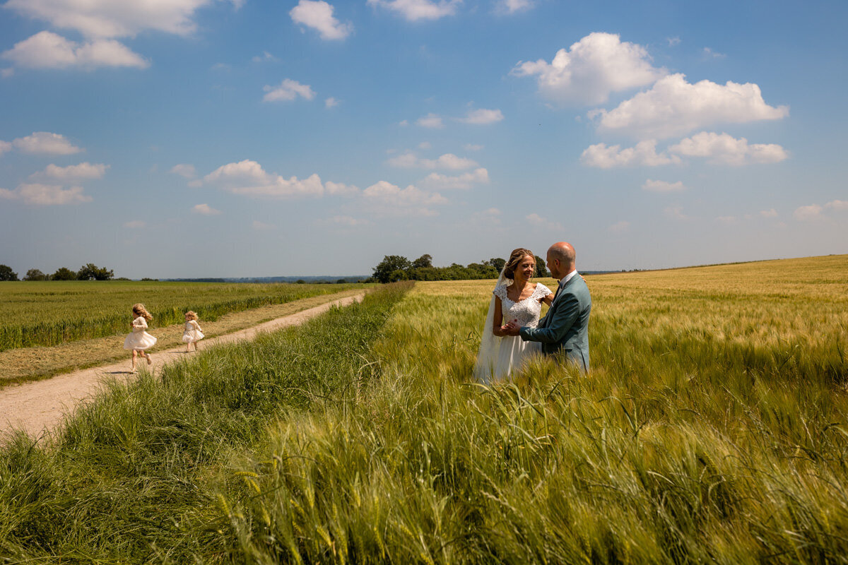 bruidspaar en kindjes in korenveld rennen