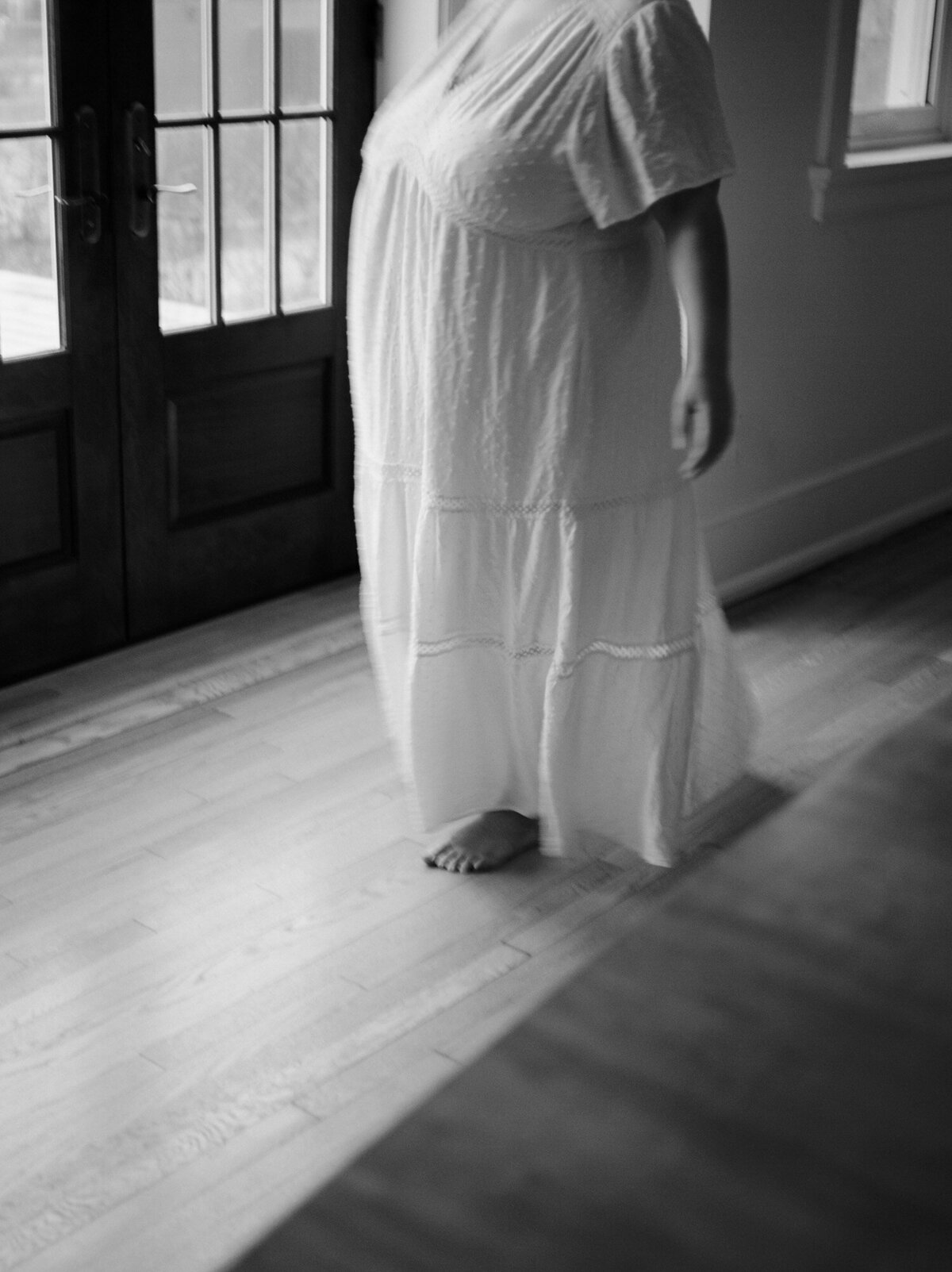 soft black and white film branding photo, woman in white cotton dress, barefoot, movement
