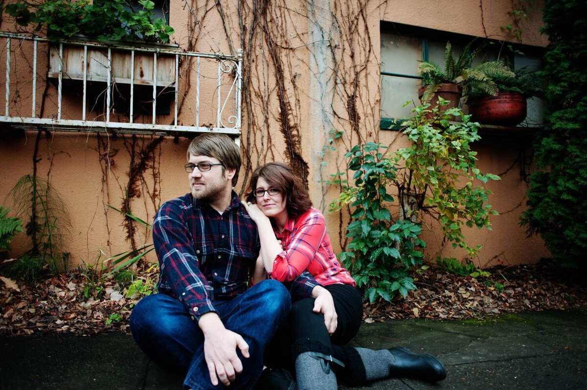 a woman leans on a mans shoulder and they sit on the sidewalk