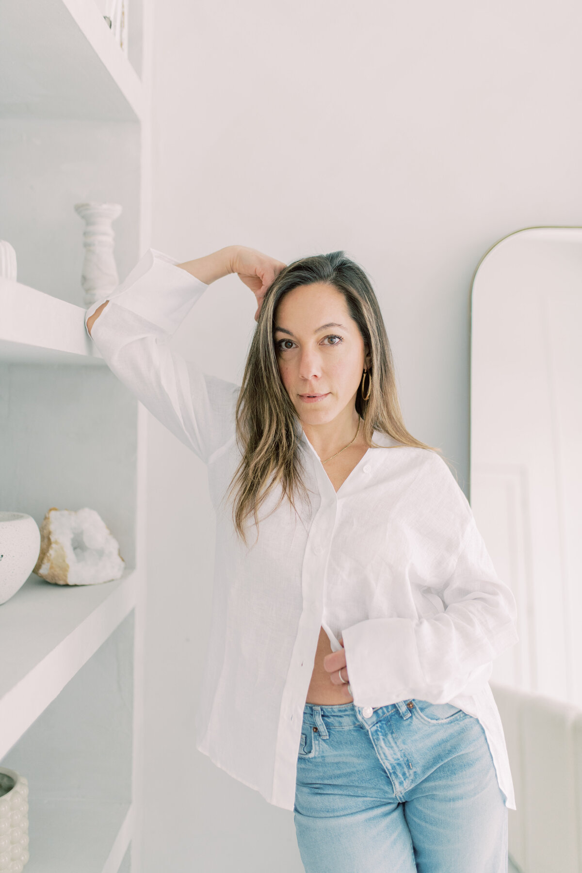 entrepreneur standing near arched shelves in a serene, light-filled studio.

