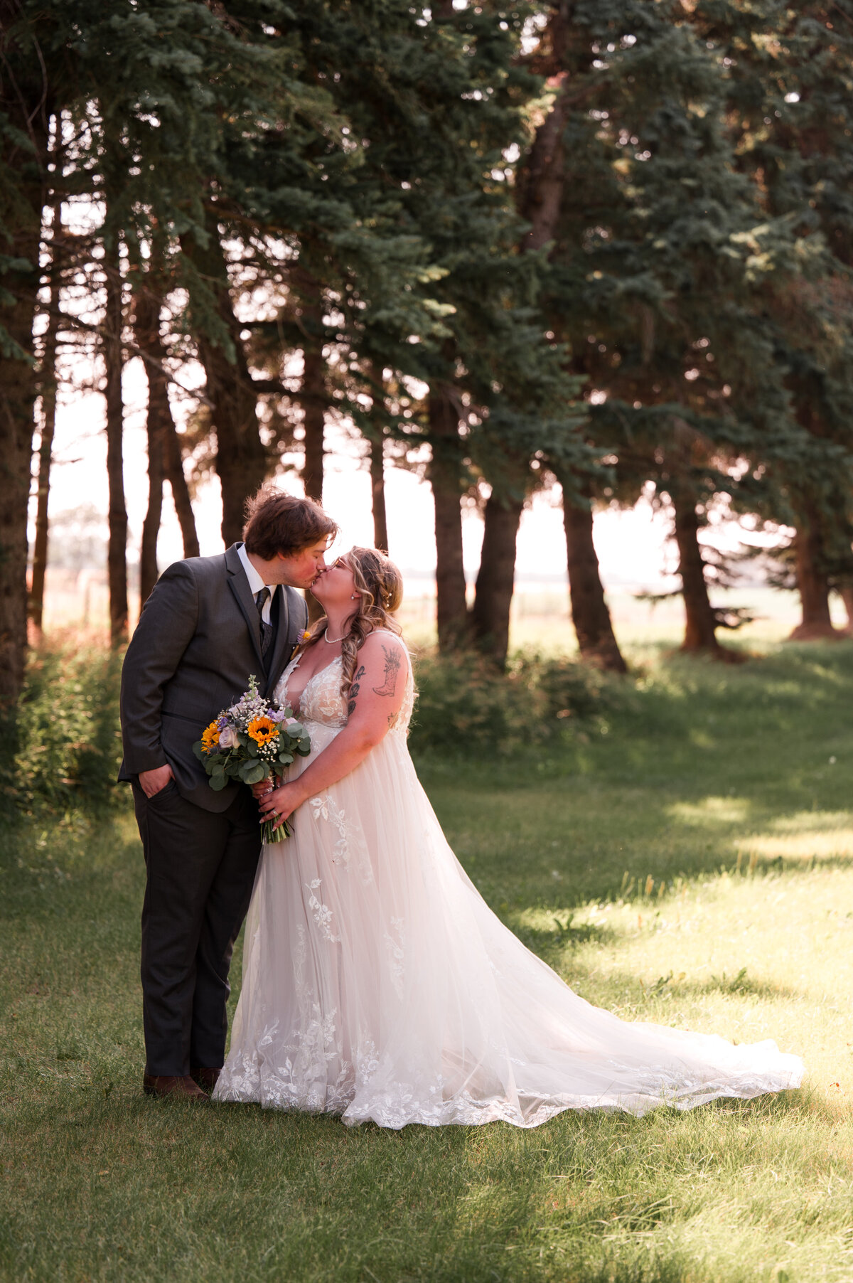 Bride and groom kissing in a field at Falkenberg stables on their wedding day