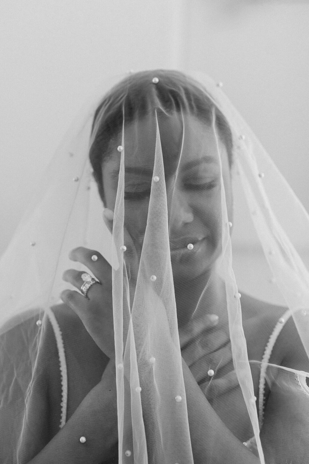 A close-up solo portrait of a bride smiling underneath her veil