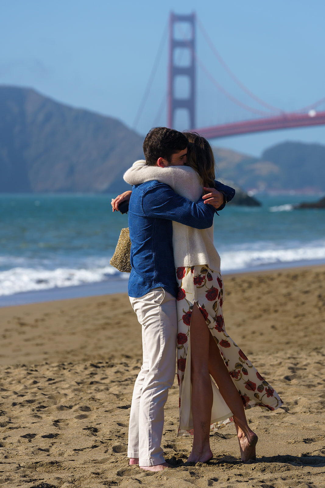 Couple kissing on a beach with the golden gate bridge n the background