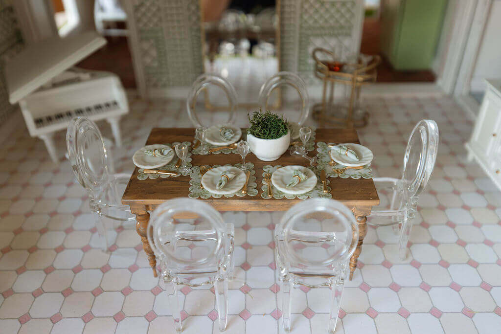 oyster creek studios petite palm beach dollhouse miniature glass chairs with plates around a wooden dining room table with white piano in dining room