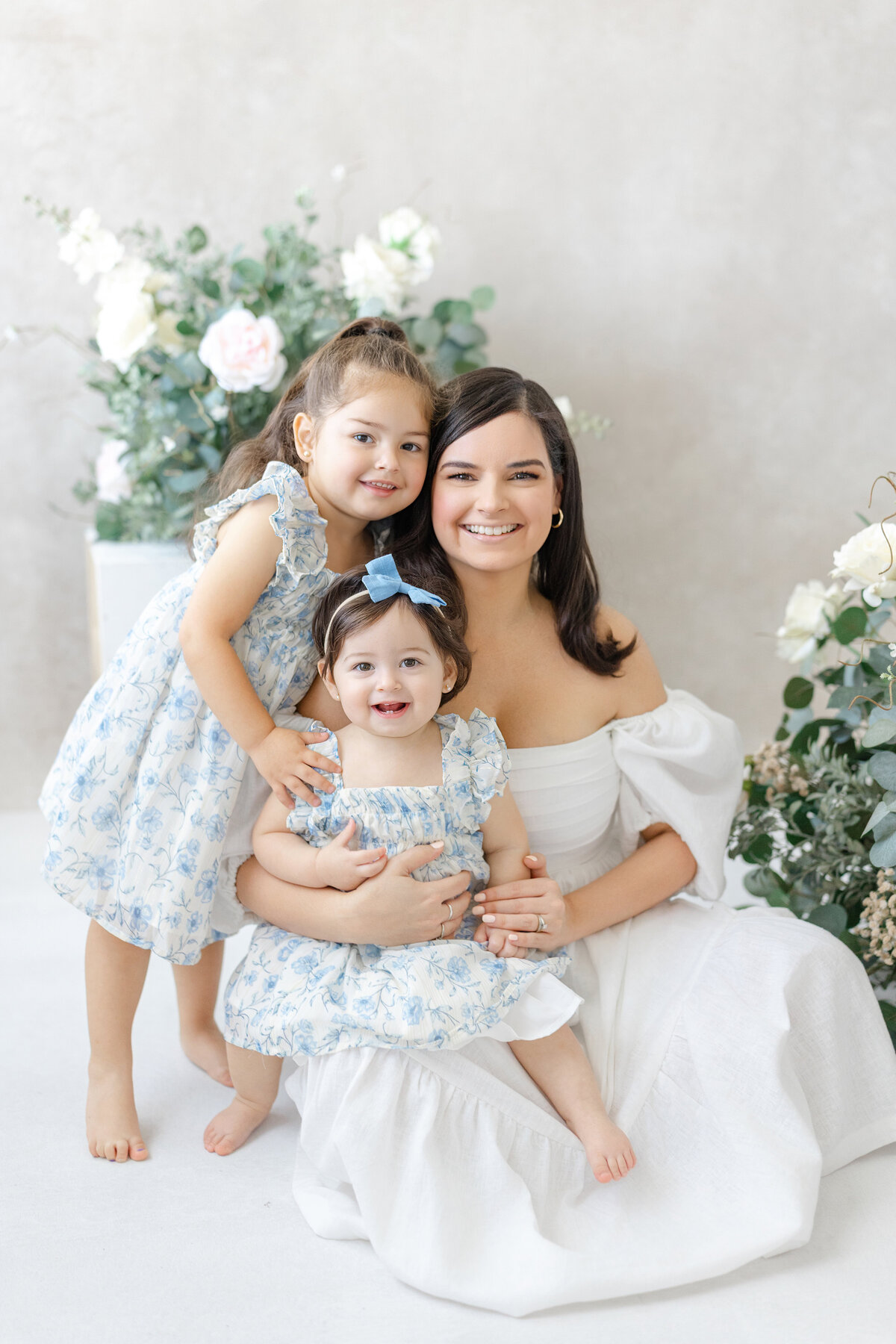 Joyful Tampa motherhood portrait of mom and daughters smiling together in soft natural light studio