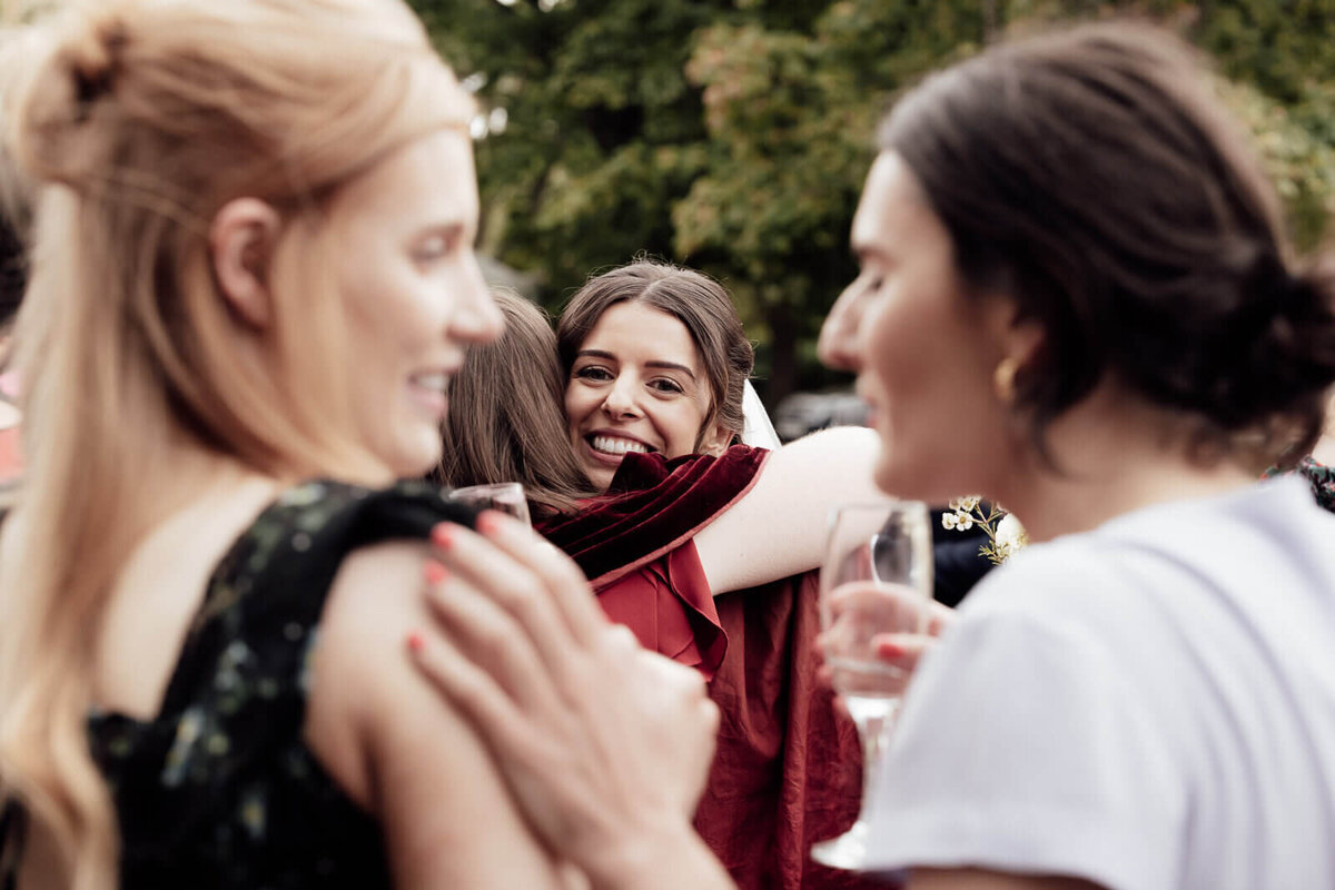 a bride hugs and smiles with guests at an Edinburgh wedding.