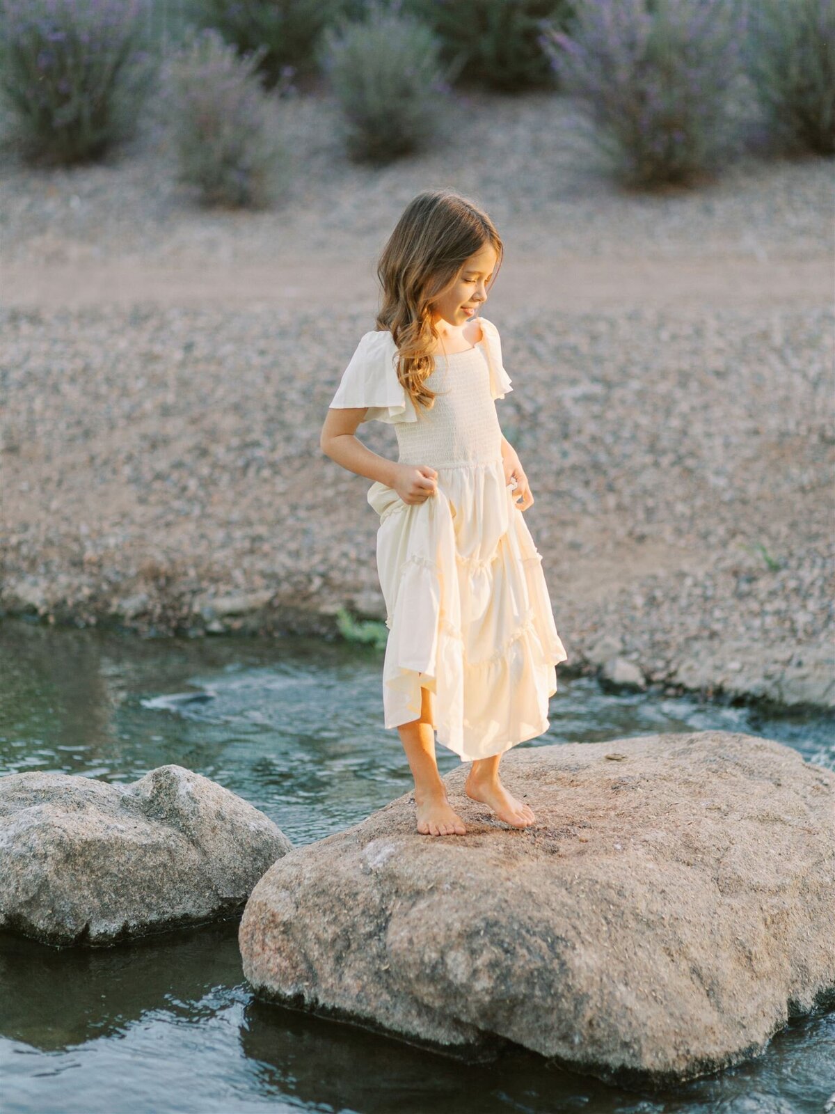 family photoshoot of toddler in river with a dress on