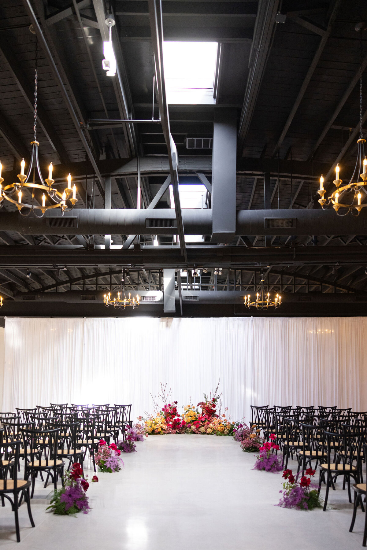 up to 200 guests in Locus for ceremony with draped backdrop and statement ground floral arch piece