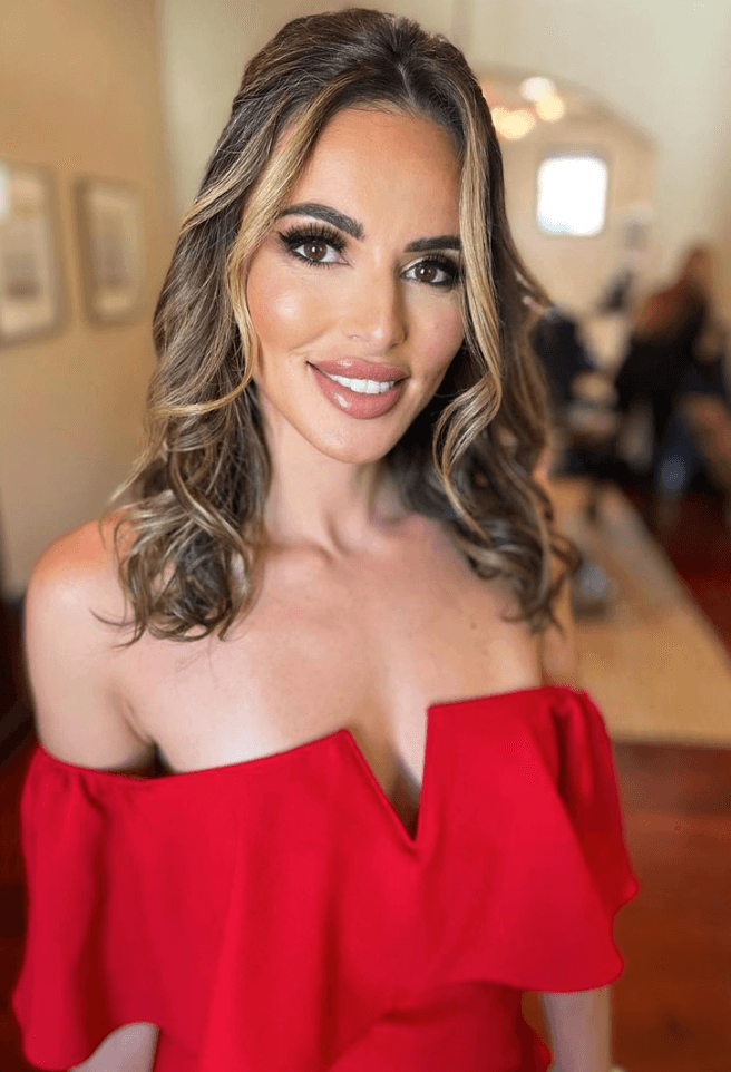Woman in red dress with full glam makeup and styled waves, ready for a professional photo shoot in Austin with Mistique Makeup