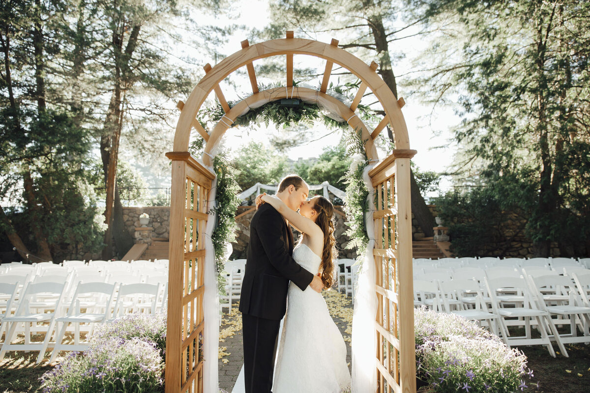 Ramsey Golf & Country Club | Wedding couple kissing under ceremony arch in morning sunlight | New Jersey